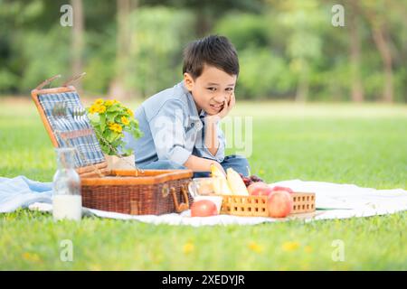 Glückliche Familie, die ein Picknick im Park genießt, mit Kindern, die Spaß im Sitzen haben, umgeben von der Natur Stockfoto