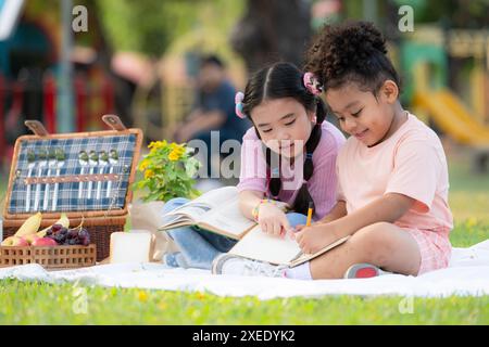 Glückliche Familie, die ein Picknick im Park genießt, Kinder haben Spaß beim Zeichnen auf Papier. Stockfoto