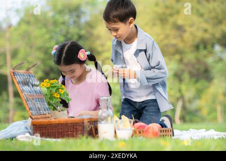 Glückliche Familie, die ein Picknick im Park genießt, Kinder sitzen zurück an Rücken und lesen Bücher. Stockfoto