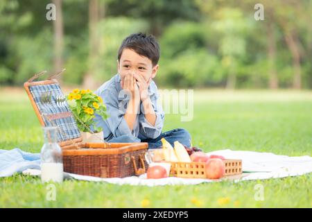 Glückliche Familie, die ein Picknick im Park genießt, mit Kindern, die Spaß im Sitzen haben, umgeben von der Natur Stockfoto