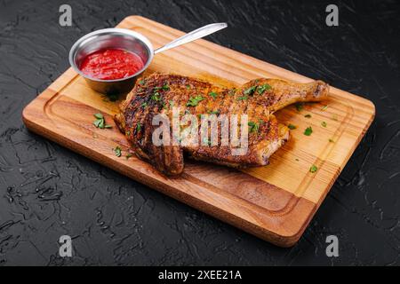 Gegrilltes knuspriges Hähnchenschenkelviertel auf dem Holzbrett Stockfoto