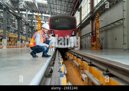 Porträt eines jungen männlichen Technikers mit einem Walkie-Talkie, der in einer Skytrain-Reparaturstation arbeitet und sitzt. Stockfoto