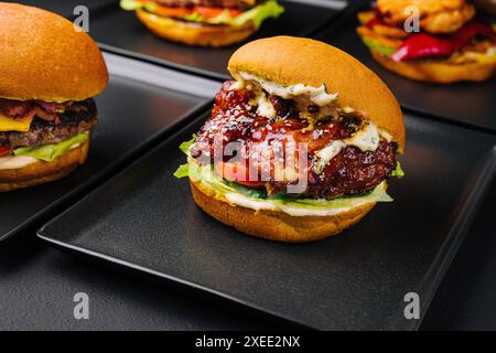 Appetitliche knusprige Hähnchenburger auf schwarzen Tellern Stockfoto