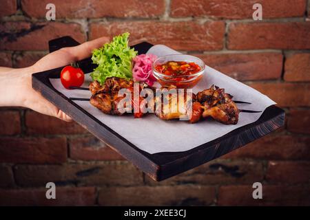 Hühnchenkebabs mit Tomatensauce auf einem Brett Stockfoto