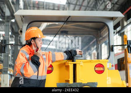 Weibliche Ingenieurin, die in einer Elektrobahn-Werkstatt arbeitet und kleine Schleifarbeiten an der Schienenmaschine überprüft, bevor sie eingesetzt wird Stockfoto