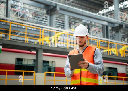 Porträt eines jungen männlichen Technikers mit einem Walkie-Talkie, der in einer Skytrain-Reparaturstation arbeitet und steht. Stockfoto