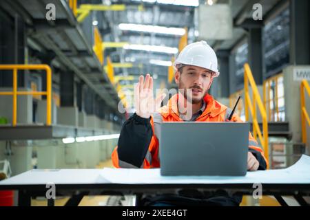 Porträt des jungen männlichen Technikers, der auf dem Tisch in der Skytrain-Reparaturstation sitzt, überprüfen Sie die Details der elektrischen Bahn repai Stockfoto