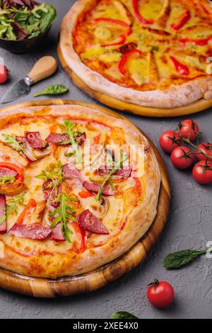 Gebackene runde Pizza mit Salami, Tomaten und Pilzen Stockfoto