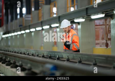 Porträt eines jungen männlichen Technikers mit einem Walkie-Talkie, der in einer Skytrain-Reparaturstation arbeitet und steht. Stockfoto