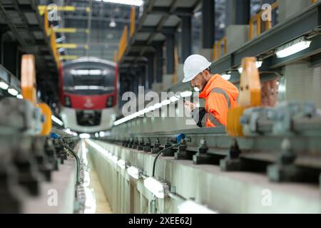 Porträt eines jungen männlichen Technikers mit einem Walkie-Talkie, der in einer Skytrain-Reparaturstation arbeitet und steht. Stockfoto