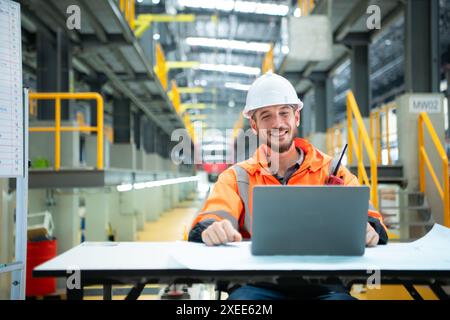 Porträt des jungen männlichen Technikers, der auf dem Tisch in der Skytrain-Reparaturstation sitzt, überprüfen Sie die Details der elektrischen Bahn repai Stockfoto