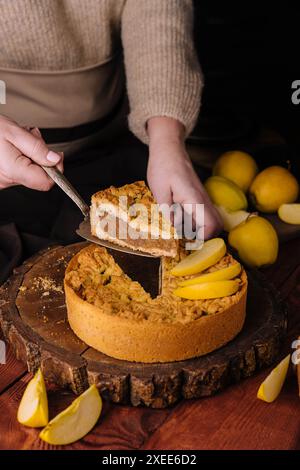 Die Frau hat ein Stück geriebene Torte mit Zitronenquark abgeschnitten Stockfoto