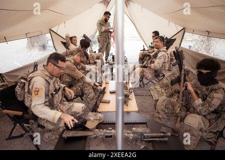 Eine Gruppe von Soldaten in Tarnuniformen hält Waffen in einem Feldzelt, plant und bereitet euch auf das Kampftraining vor. Stockfoto