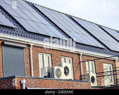 Luftquellenwärmepumpeneinheit, die im Freien in einem modernen Haus mit Solarpaneelen in den Niederlanden installiert wird Stockfoto
