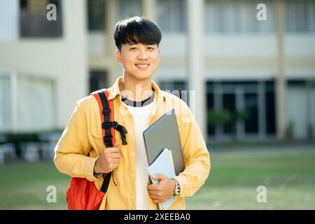 Lächelnder Student mit Laptop und Büchern auf dem Campus Stockfoto
