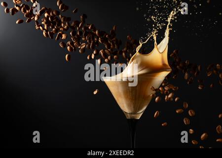 Espresso Martini-Getränk mit Spritzern und fallenden Kaffeebohnen auf schwarzem Hintergrund. Kopierbereich. Stockfoto