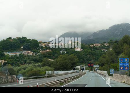 Menton, Frankreich - 12. Mai 2023: Eine Autobahn mit Tunneleingang, die in eine malerische Bergregion in Frankreich führt. Die Straße ist gesäumt von üppigem greene Stockfoto