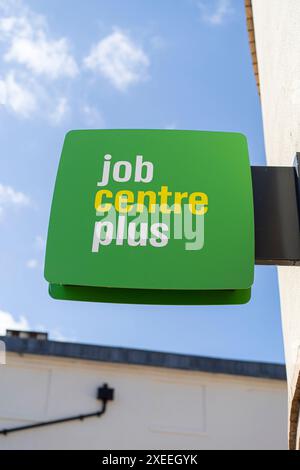 Nahaufnahme eines grünen Job Centre Plus-Schilds, das auf einem britischen Gebäude im Freien mit blauem Himmel isoliert ist. Stockfoto