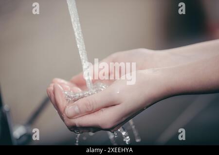 Zwei Hände werden unter fließendem Wasser gehalten und fangen die Flüssigkeit in ihren Handflächen auf. Das Bild weckt ein Gefühl von Sauberkeit und Hygiene Stockfoto