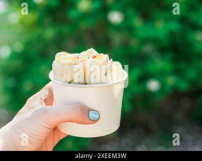 Hand hält gerolltes Eis in Konusbecher Stockfoto