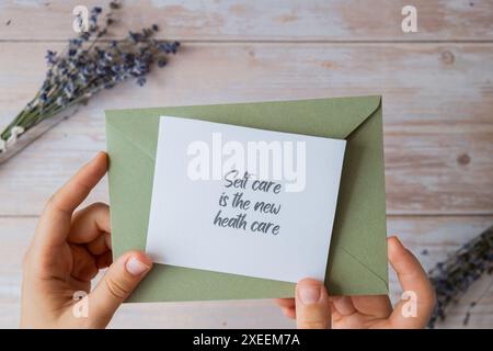 SELF CARE IST DER NEUE GESUNDHEITSTEXT auf unterstützender Nachricht Papier Notiz Erinnerung aus grünem Umschlag. Flache Zusammensetzung trocken la Stockfoto