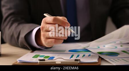 Männliche Hand in Anzug halten siver Stift im Büro mit Klemmbrett auf Tisch Nahaufnahme. Umfassende Prüfung des Unternehmensgeschäfts in allen Phasen der Entwicklung. Stockfoto