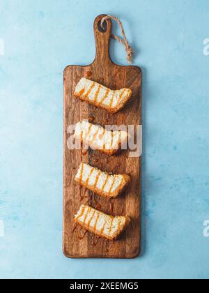 Cheesekace-Stücke auf Schneidebrett über blauer Tischplatte Stockfoto