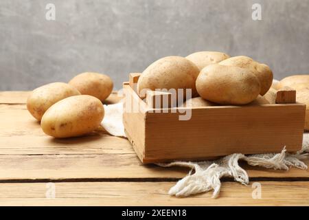 Viele frische Kartoffeln in Kiste auf Holztisch Stockfoto