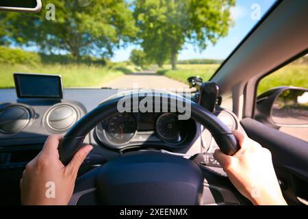 POV-Aufnahme von Frauenhand am Lenkrad, das entlang der Country Road fährt Stockfoto