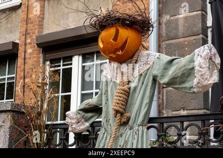 Außen wunderschöner atmosphärischer halloween-Vogelscheuchen-Kürbis, dekoriert auf der Veranda. Herbstlaub und Herbstblumen feiern Stockfoto