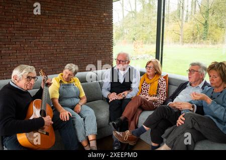 Gemütlicher Nachmittag: Senioren genießen Musik und Gesellschaft auf einem bequemen Sofa Stockfoto