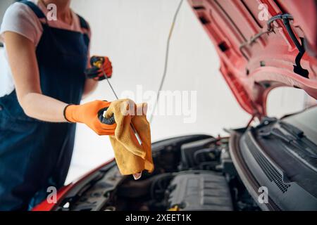 Nahaufnahme Einer Automechanikerin, Die Unter Der Motorhaube Des Fahrzeugs Den Ölstand Mit Dem Messstab Überprüft Stockfoto