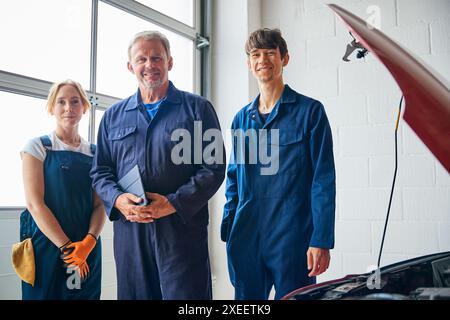 Porträt Des Teams Von Automechanikern In Der Garage Mit Trainee In Der Hand Eines Digitalen Tablets Stockfoto