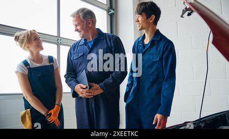 Team Von Automechanikern In Der Garage Mit Trainee, Der Ein Digitales Tablet Hält Stockfoto