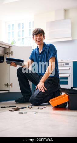 Porträt Des Männlichen Klempners Mit Digital Tablet Befestigung Abfallentsorgungseinheit In Haushaltsspüle Stockfoto