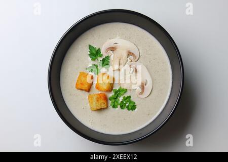 Pilzcremesuppe mit Creme, Croutons und Kräutern auf weißem Holzhintergrund. Köstliches Komfortessen Stockfoto