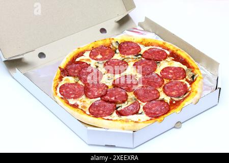 Frisch gebackene Pizza mit Wurst in einem Karton auf weißem Hintergrund Stockfoto