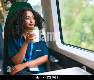 Ärztin Oder Krankenschwester Pendeln Im Zug Mit Wiederverwendbarer Kaffeetasse Und Blick Aus Dem Fenster Stockfoto