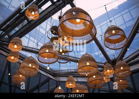 Lampen mit Korbschirmen unter einer Glasdecke im modernen Business Center oder Restaurant. Stockfoto