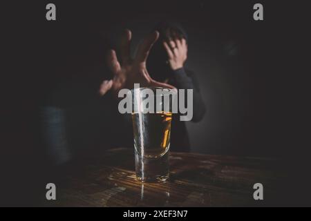 Porträt eines einsamen, depressiven, jungen Mannes, der nach einem Whiskey auf einer Holzbar greift. Stockfoto