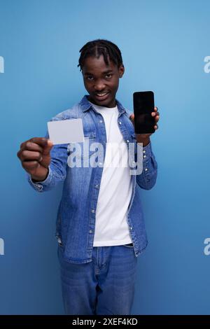 Stilvoller amerikanischer Mann mit schwarzen Dreadlocks, die Geldkartenmockup halten Stockfoto