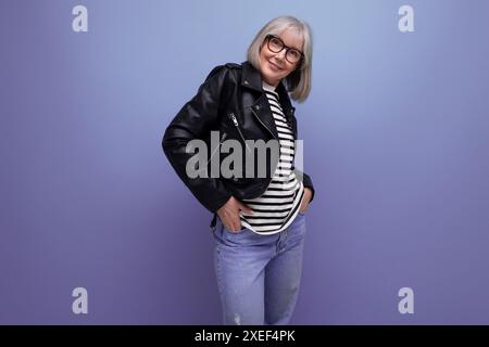 Entzückende grauhaarige 60er Jahre reife Frau in einer stilvollen Jacke auf einem hellen Hintergrund Stockfoto