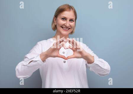 Nette angenehme blonde reife Frau mit sauberem Gesicht im Menopauenalter im Studiohintergrund Stockfoto