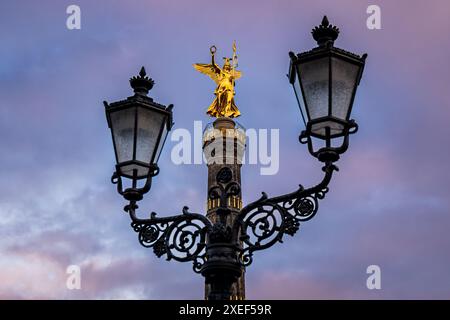 Die Siegessäule Berlin strahlt im goldenen Licht der Abendsonne, umgeben von Laternen, die ihre strahlende Schönheit unterstreichen. Stockfoto