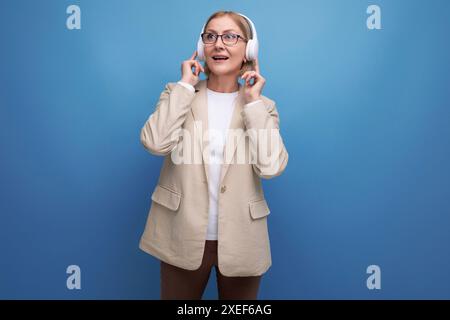 50s eine Frau in einer Jacke beherrscht die Technik, Musik über Kopfhörer im Studiohintergrund zu hören Stockfoto