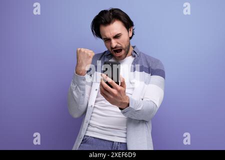 Ein glücklicher Brünette-Typ im lässigen Stil mit einem Smartphone in der Hand Stockfoto