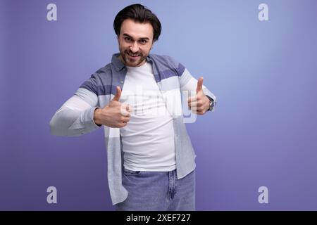 Energiegeladener junger Brünette Mann im Model-Auftritt auf Atelierhintergrund Stockfoto