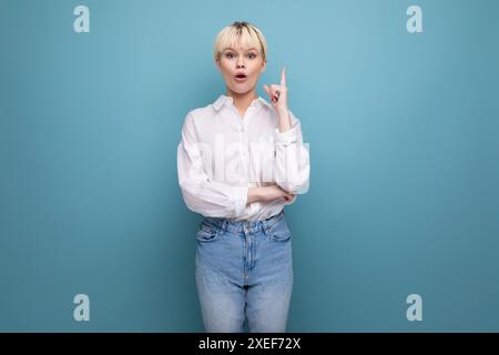Die junge, kluge blonde Sekretärin in einem weißen Hemd zeigt ihren Finger mit Inspiration auf den Stein. Geschäftskonzept Stockfoto