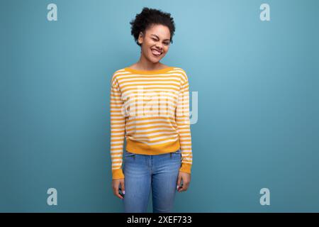 Attraktive junge lateinische Frau mit Afro-Haaren in einer gelb gestreiften Bluse Stockfoto