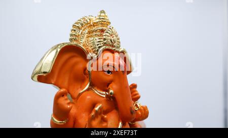 Wunderschönes Lord Ganesha Idol auf weißem Hintergrund. Orangefarbene Ganpati-Murti-Statue Stockfoto